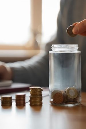 A person dropping a coin into a jar.